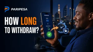 Close-up of a smartphone showing a mobile money withdrawal confirmation glow, dark warm-toned lighting